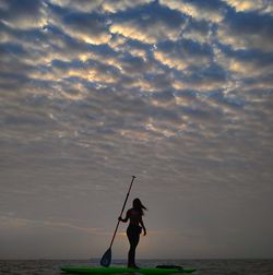 Man standing at beach against sky during sunset