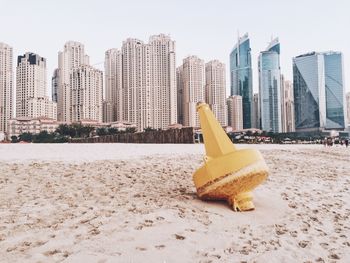 Distance marker at beach against modern buildings in city