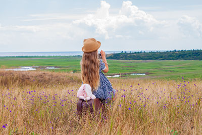 Child girl in straw hat and dress sitting on vintage suitcase reading book. cute kid with soft  toy 