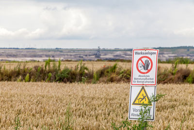 Information sign on field against sky