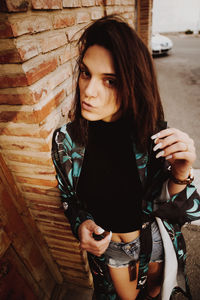Portrait of young woman puckering while standing against brick wall