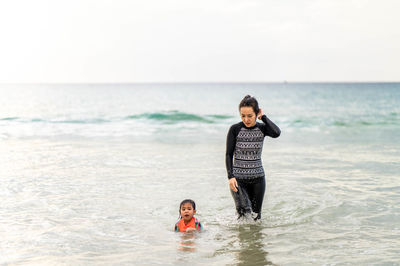 Full length of father and daughter on beach against sky