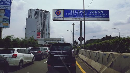 Road sign against sky in city