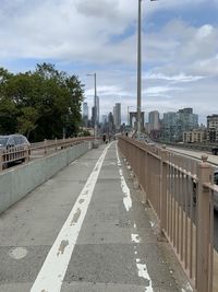 Road amidst buildings against sky at brooklyn bridge 