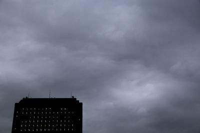 Low angle view of communications tower against cloudy sky