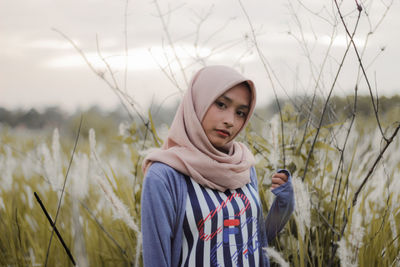 Portrait of young woman standing on field