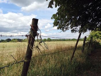 Fence on field against cloudy sky