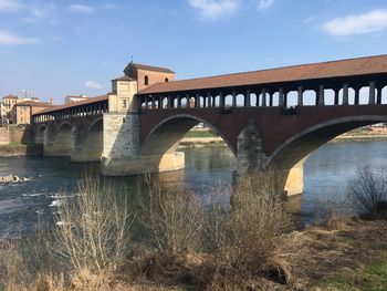 Arch bridge over river against sky