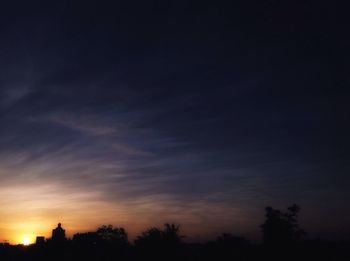 Low angle view of silhouette trees against sky