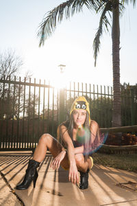 Portrait of smiling young woman against palm trees