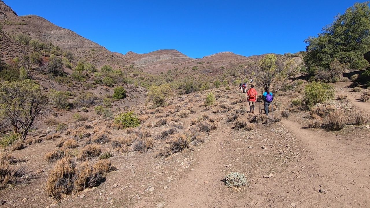 PEOPLE WALKING ON MOUNTAIN AGAINST SKY