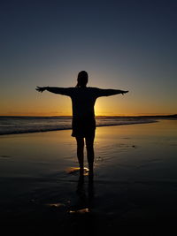 Full length of silhouette man standing on beach against sky during sunset