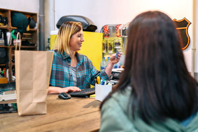 Woman shop assistant registering client data in store terminal to make invoice of purchased clothing