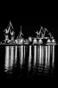 Illuminated built structure by sea against clear sky at night