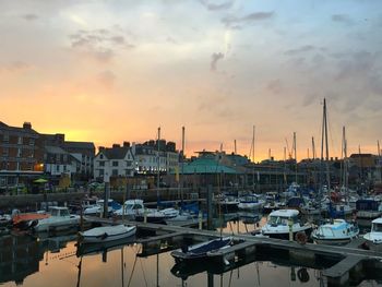 Boats moored at harbor during sunset