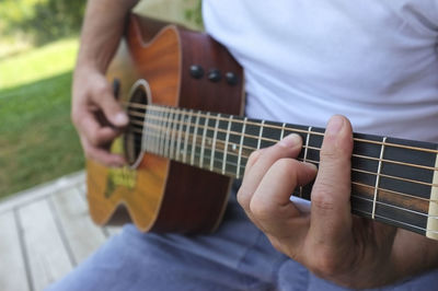 Midsection of man playing guitar