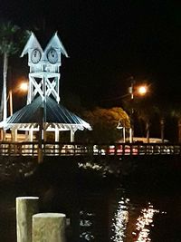 Illuminated street light by building against sky at night