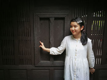 Smiling girl standing against wooden wall