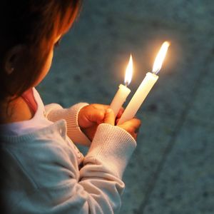 High angle view of girl holding illuminated candles on footpath