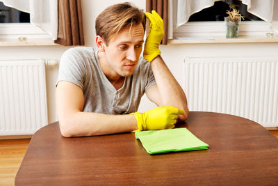 Young man cleaning table at home