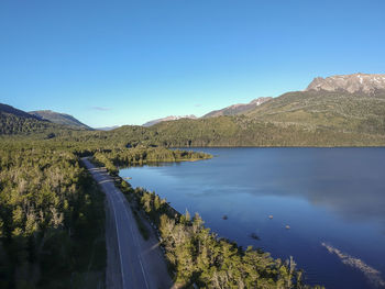 Scenic view of lake and mountains against clear blue sky