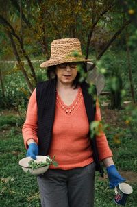 Mid adult man wearing hat while holding plants