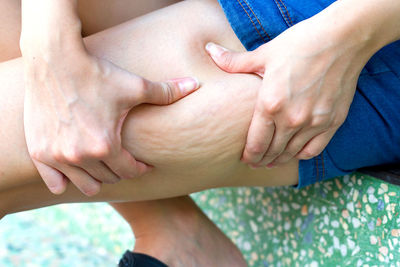 Midsection of woman with holding thigh while sitting on seat