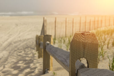 Wooden post on sand at beach against sky