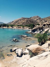 Scenic view of calm sea by mountains against blue sky