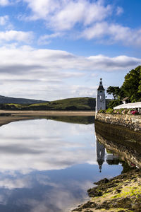 Reflection of sky and bell tower in lake