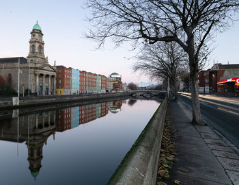 Canal amidst buildings in city against sky