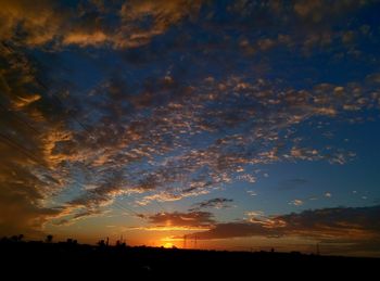 Scenic view of dramatic sky over silhouette landscape during sunset