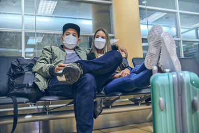 Happy young loving couple waiting for boarding in airport terminal. they are embracing and smiling