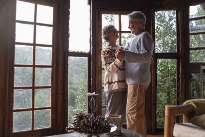 Happy smiling couple dancing by window