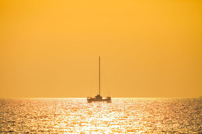 Sailboat sailing on sea against sky during sunset