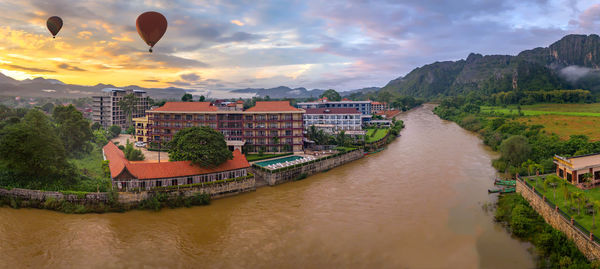 River amidst buildings against sky during sunset