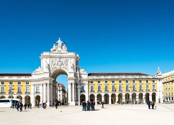 People by rua augusta against clear blue sky