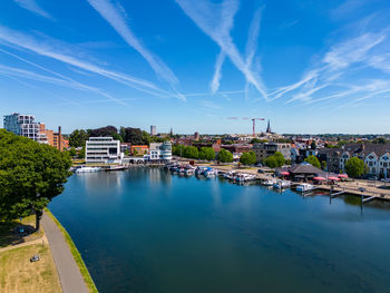 Buildings by river against sky