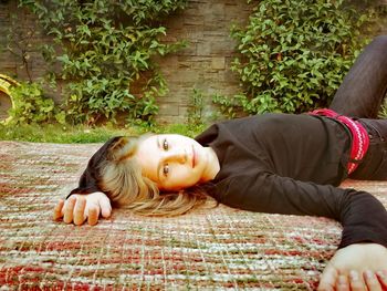 Portrait of young woman lying on rug in yard