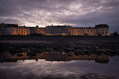 Buildings by sea against sky at sunset