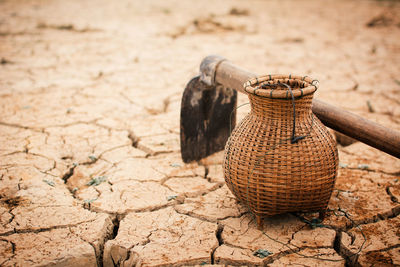 Close-up of garden hoe and basket on barren land