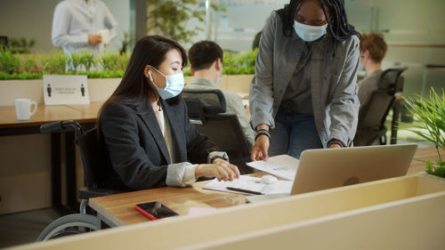 Businesswomen wearing mask having discussion at office