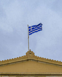 Low angle view of flag against building against sky