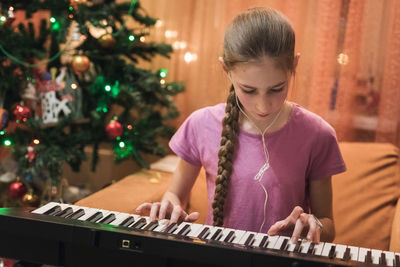 Full length of girl sitting on christmas tree