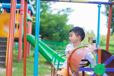 Side view of boy playing on slide at playground