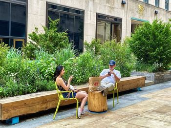 People sitting by potted plants