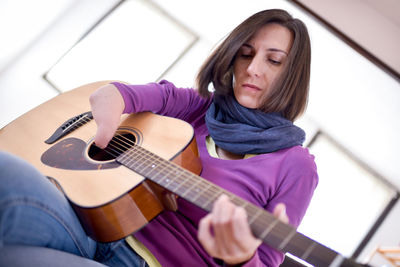 Woman playing guitar at home