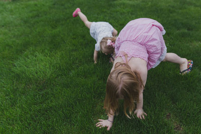 High angle view of sisters playing on grassy field at park