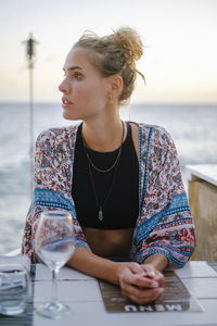 Portrait of young woman sitting at beach restaurant