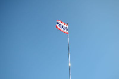 Low angle view of flag against clear blue sky